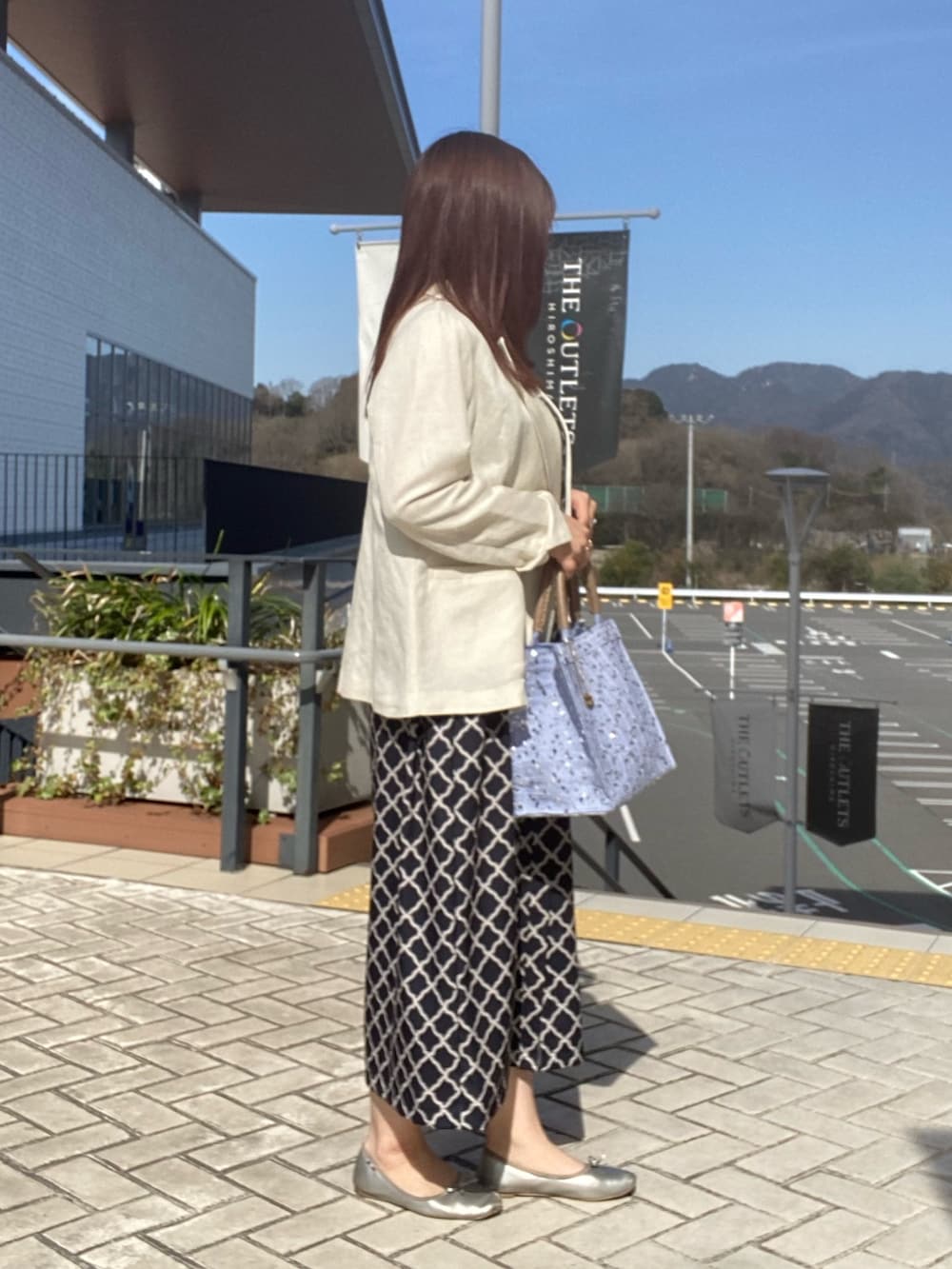 ブラック系のワンピース、ホワイト系のテーラードジャケットを着用したレディースの春コーディネートの2枚目の写真