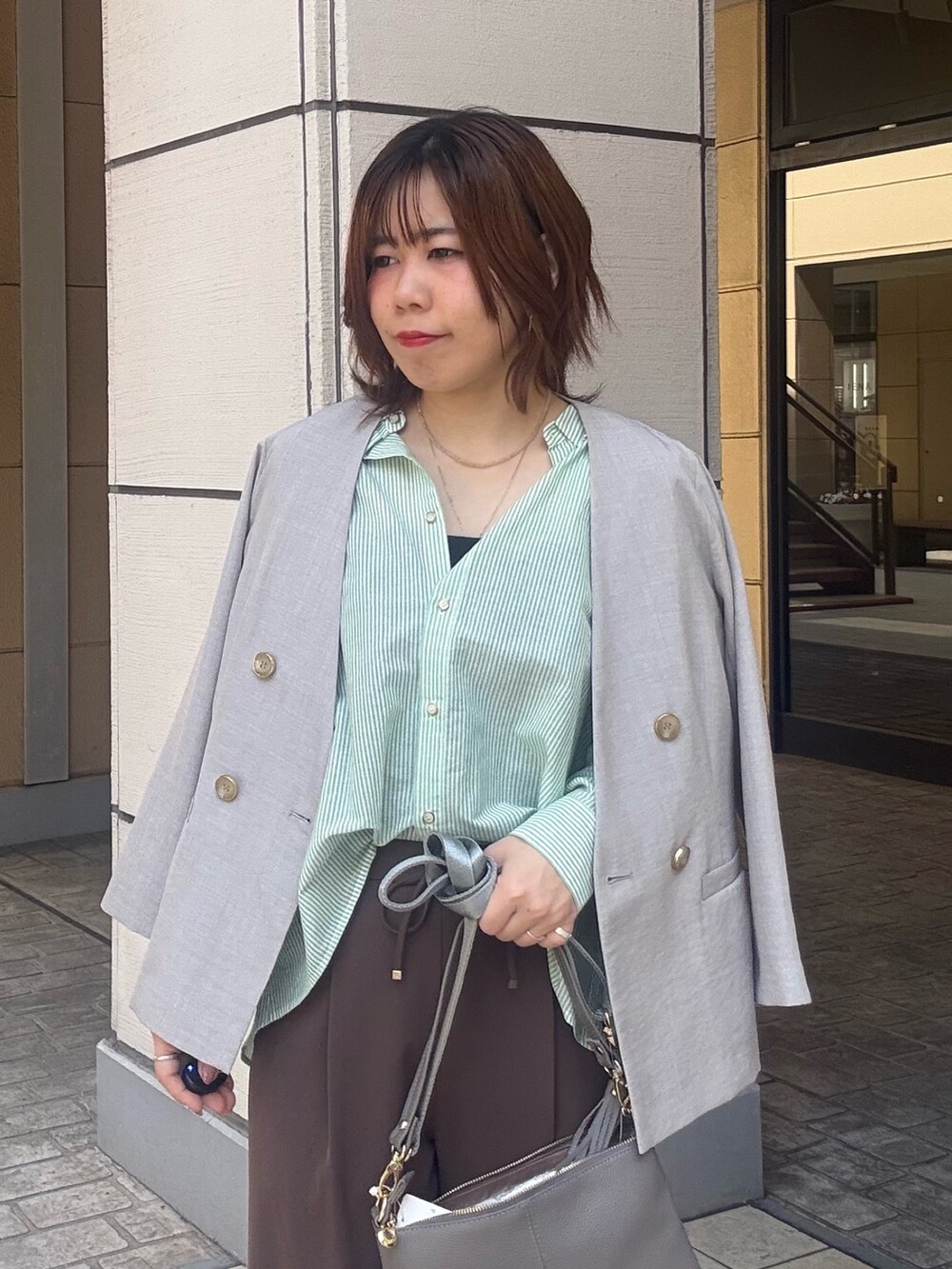 グレー系のショルダーバッグ、ブラウン系のその他パンツ、ベージュ系のダウンジャケット/コートを着用したレディースの春コーディネートの4枚目の写真