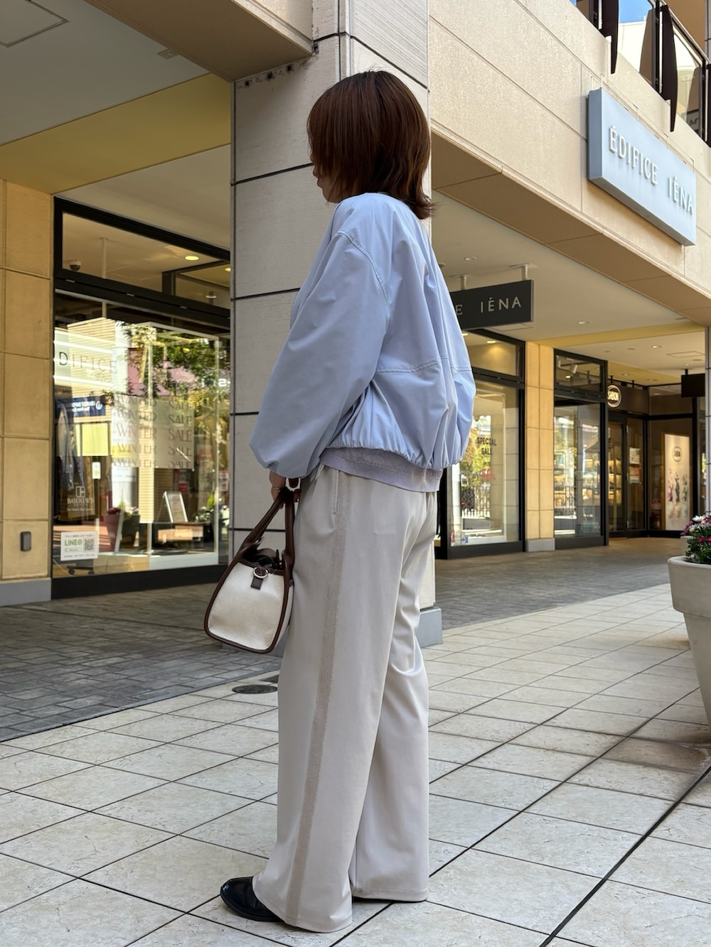 ブルー系のブルゾン、パープル系のニット/セーター、ホワイト系のTシャツ/カットソーを着用したレディースの春コーディネートの2枚目の写真