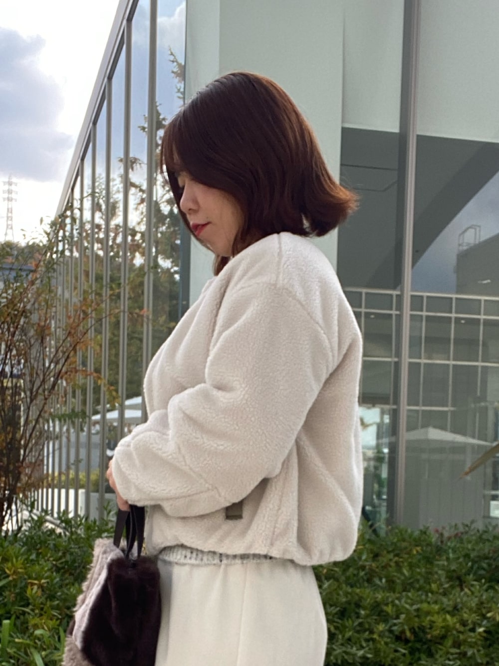 グリーン系のブルゾン、グレー系のニット/セーター、ホワイト系のスカートを着用したレディースの冬コーディネートの5枚目の写真