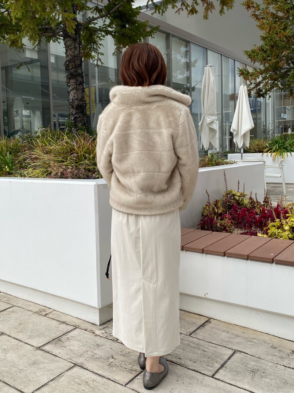 ホワイト系のブルゾン、グレー系のニット/セーター、ホワイト系のスカートを着用したレディースの冬コーディネートの3枚目の写真