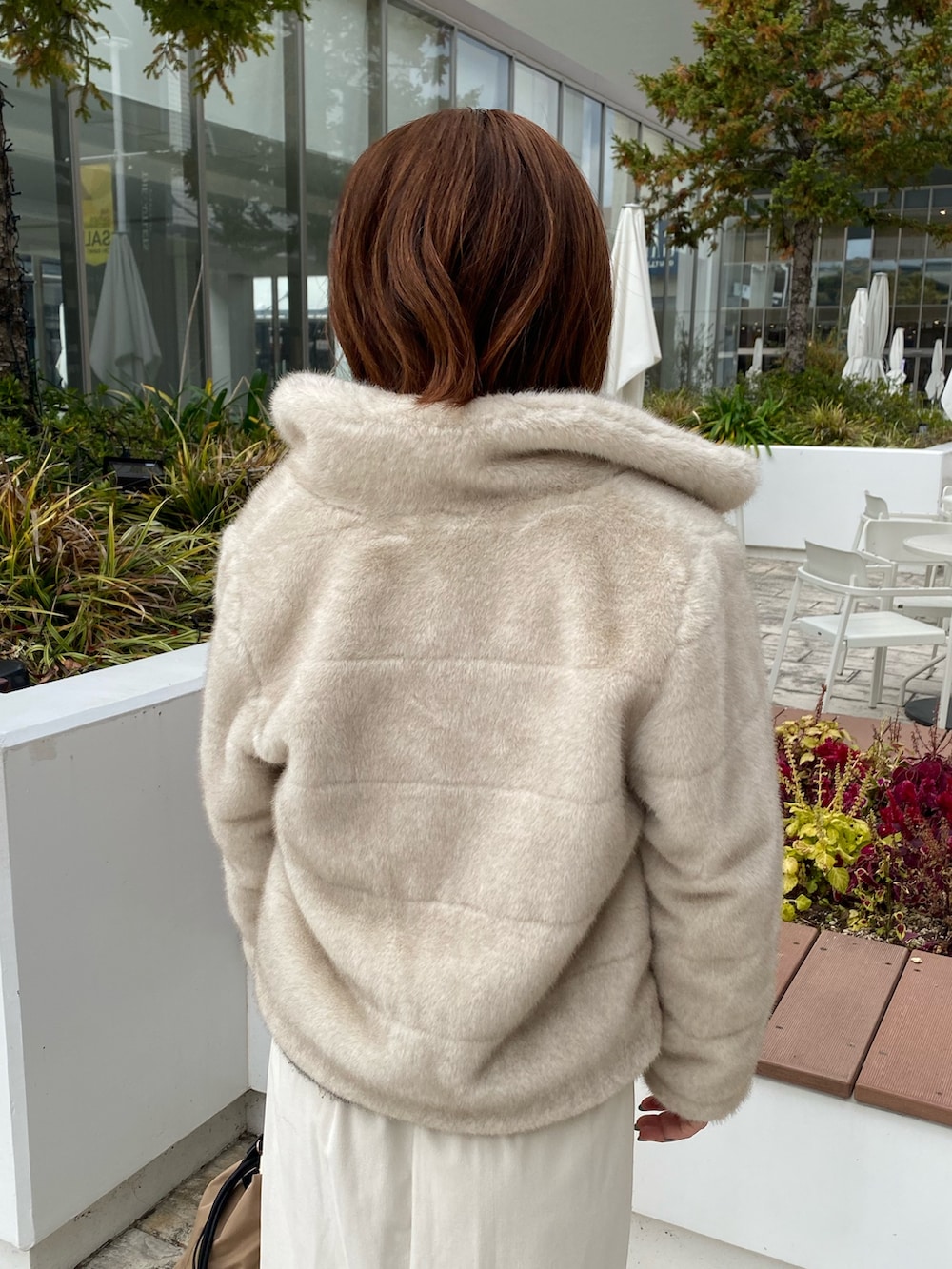 ホワイト系のブルゾン、グレー系のニット/セーター、ホワイト系のスカートを着用したレディースの冬コーディネートの6枚目の写真