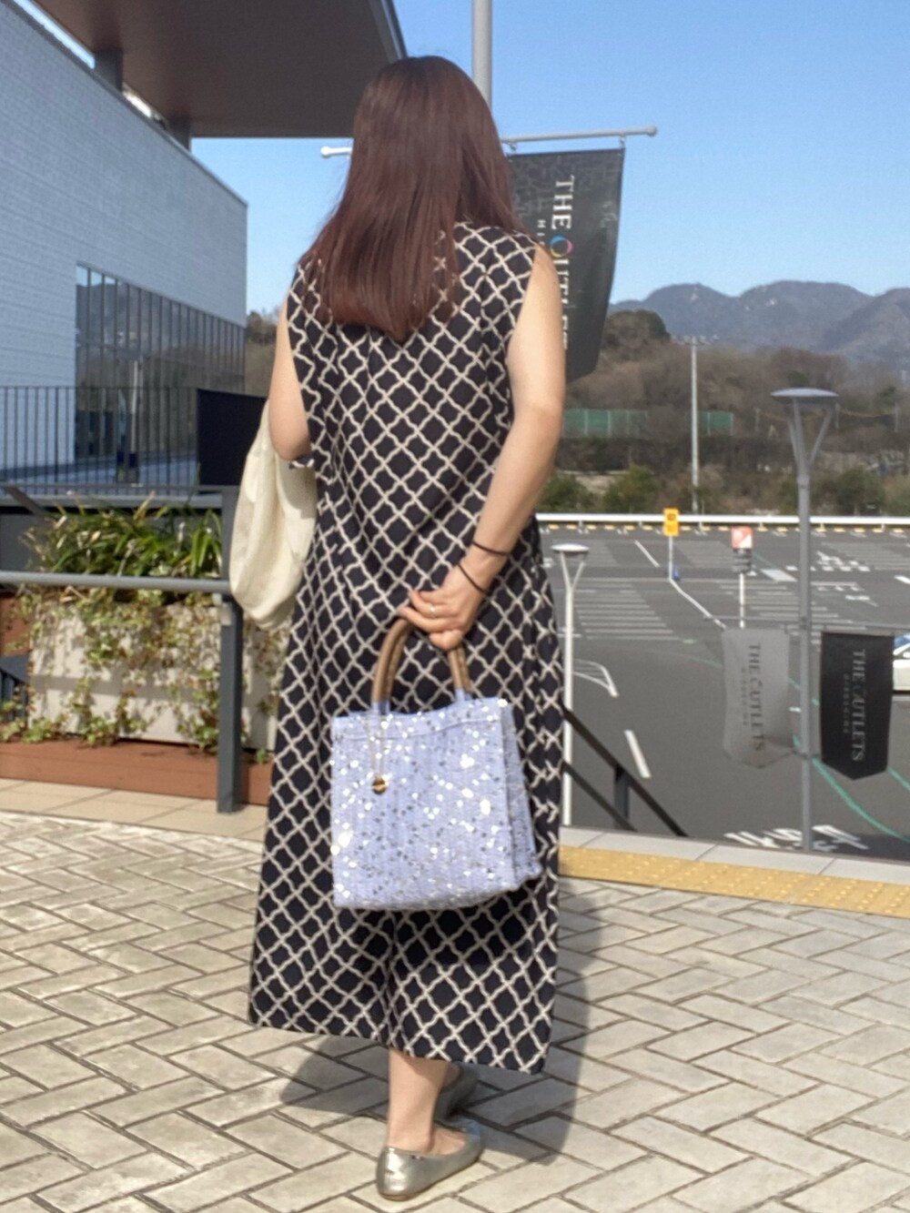 ブラック系のワンピース、ホワイト系のテーラードジャケットを着用したレディースの春コーディネートの3枚目の写真