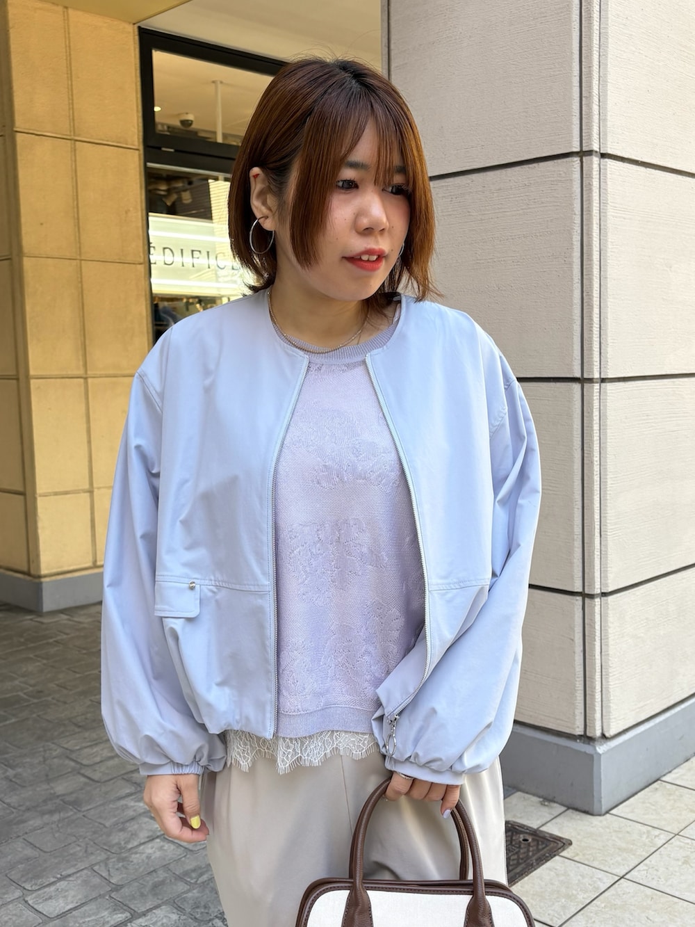 ブルー系のブルゾン、パープル系のニット/セーター、ホワイト系のTシャツ/カットソーを着用したレディースの春コーディネートの4枚目の写真