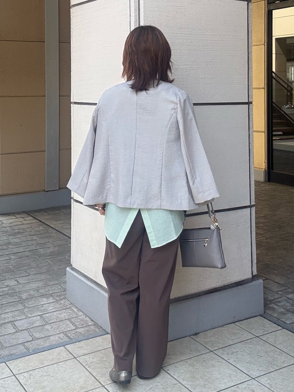 グレー系のショルダーバッグ、ブラウン系のその他パンツ、ベージュ系のダウンジャケット/コートを着用したレディースの春コーディネートの3枚目の写真
