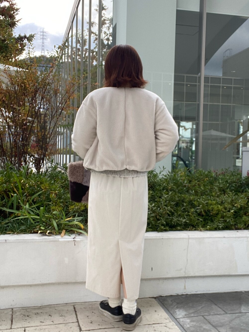 グリーン系のブルゾン、グレー系のニット/セーター、ホワイト系のスカートを着用したレディースの冬コーディネートの3枚目の写真