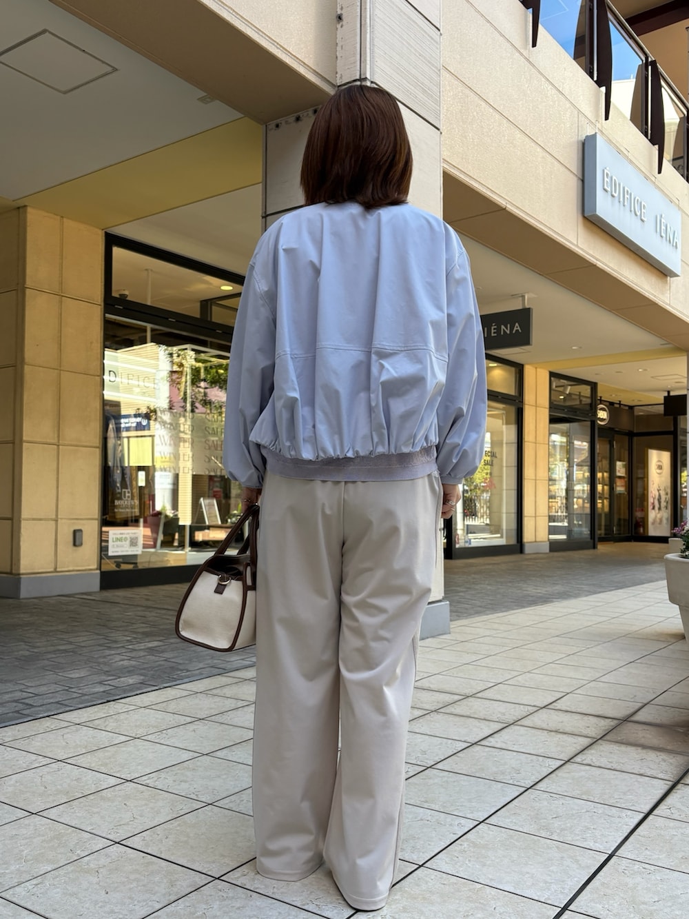 ブルー系のブルゾン、パープル系のニット/セーター、ホワイト系のTシャツ/カットソーを着用したレディースの春コーディネートの3枚目の写真