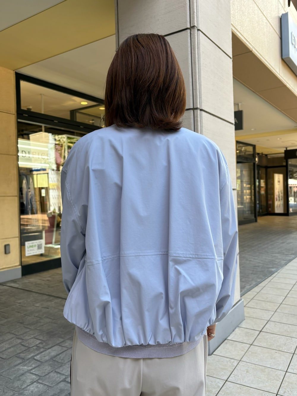 ブルー系のブルゾン、パープル系のニット/セーター、ホワイト系のTシャツ/カットソーを着用したレディースの春コーディネートの6枚目の写真