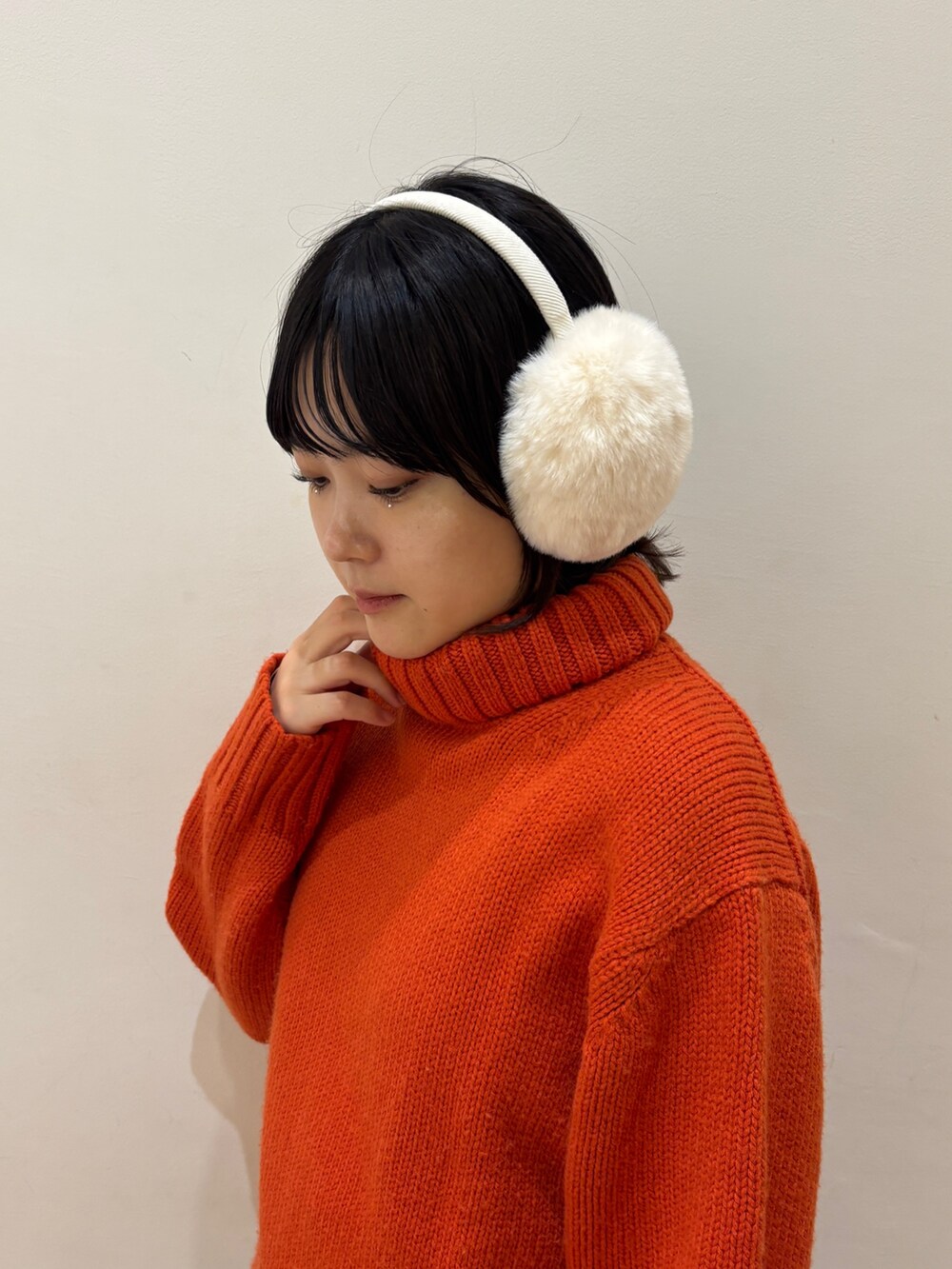 オレンジ系のニット/セーター、ブルー系のスカート、ホワイト系のイヤーマフを着用したレディースの秋コーディネートの3枚目の写真