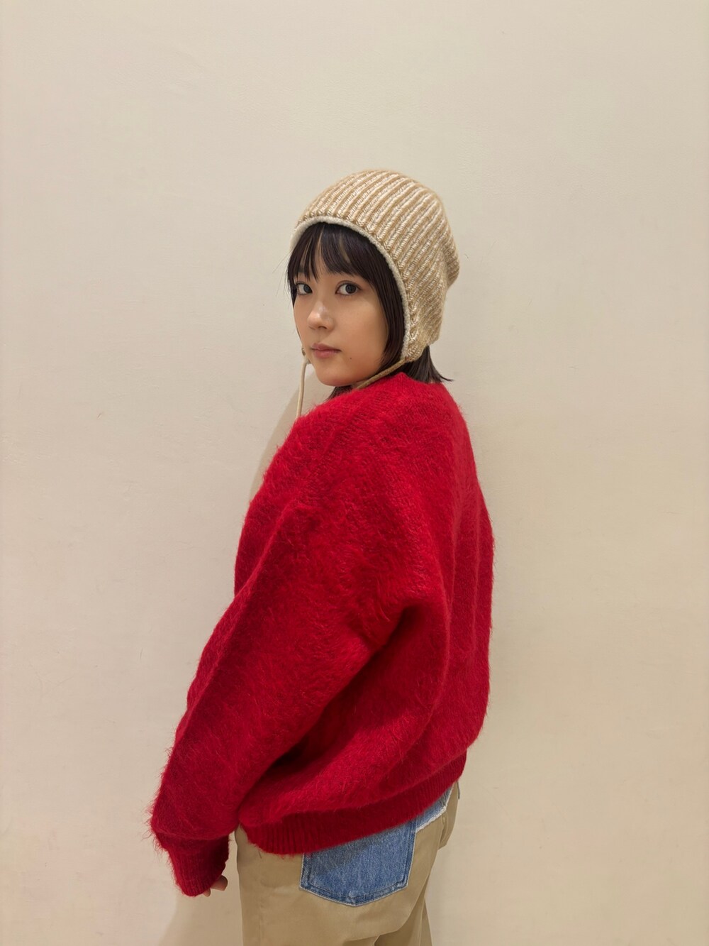 レッド系のニット/セーター、ブルー系のチノパンツ、ベージュ系のニットキャップ/ビーニーを着用したレディースの秋コーディネートの4枚目の写真