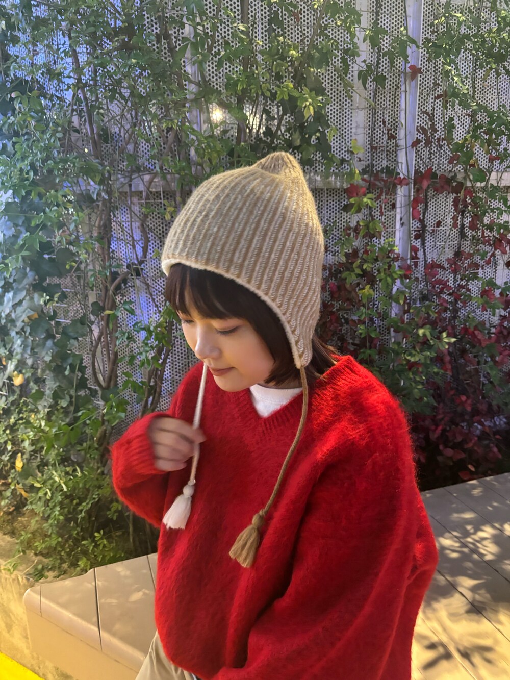 レッド系のニット/セーター、ブルー系のチノパンツ、ベージュ系のニットキャップ/ビーニーを着用したレディースの秋コーディネートの5枚目の写真