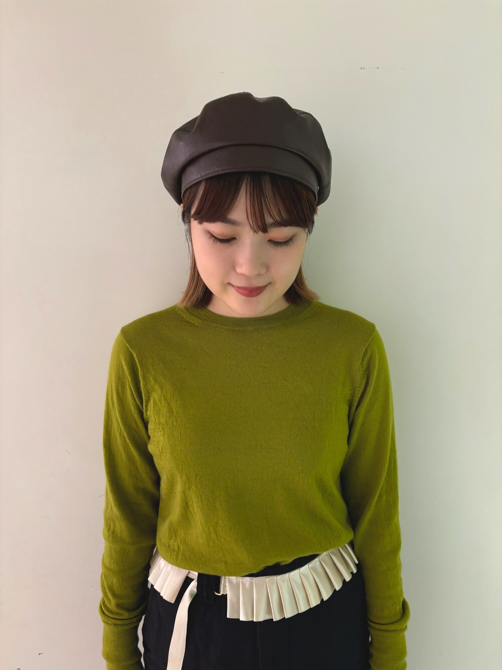 グリーン系のニット/セーター、ブラック系のチノパンツ、ブラウン系のハンチング/ベレー帽を着用したレディースの秋コーディネートの2枚目の写真