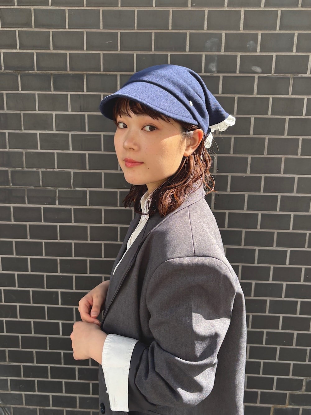 グレー系のテーラードジャケット、ブルー系のデニムスカート、ベージュ系のブーツを着用したレディースの春コーディネートの4枚目の写真