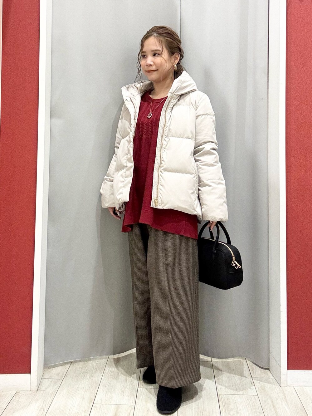 ベージュ系のダウンジャケット/コート、レッド系のニット/セーター、ベージュ系のその他パンツを着用したレディースの冬コーディネートの2枚目の写真