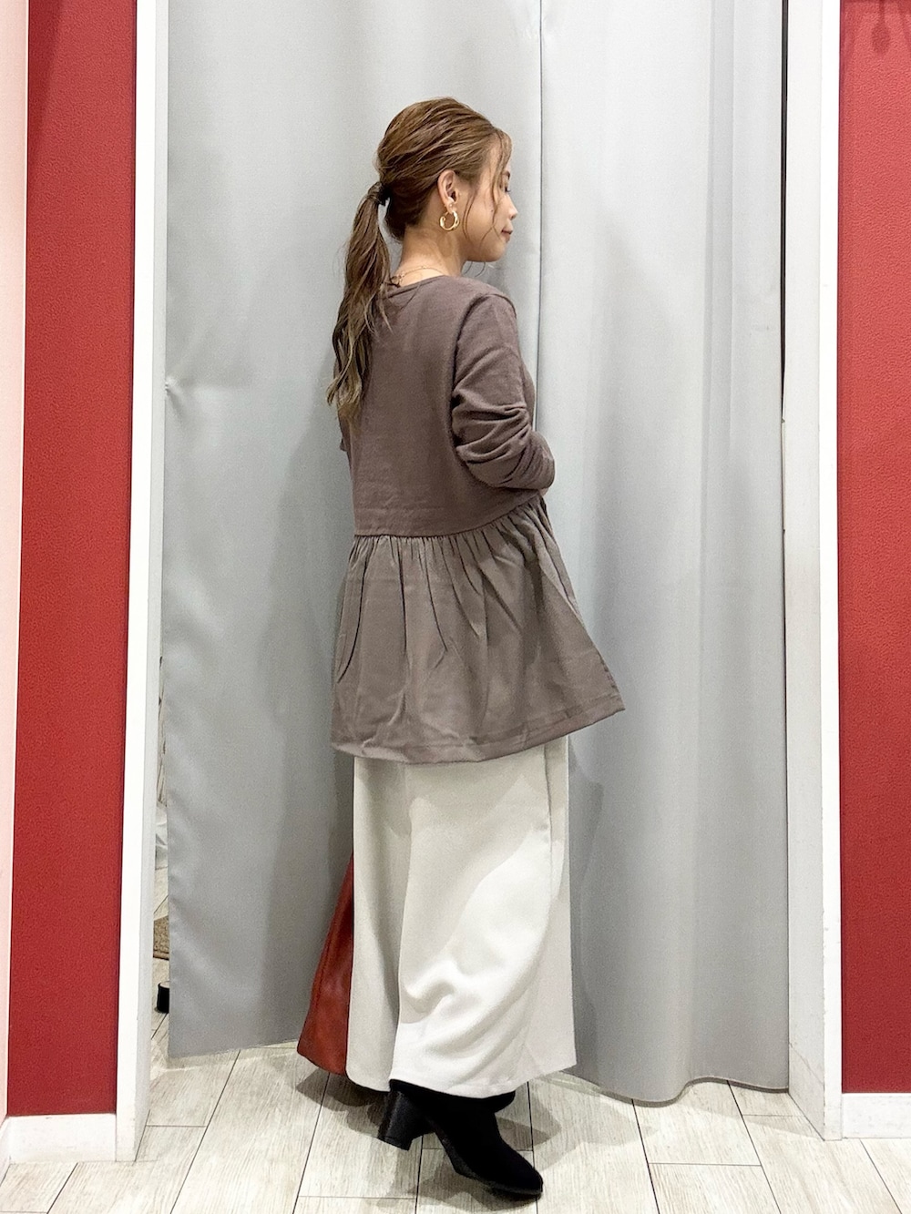 ブラウン系のニット/セーター、ベージュ系のその他パンツ、ブラック系のブーツを着用したレディースの秋コーディネートの9枚目の写真