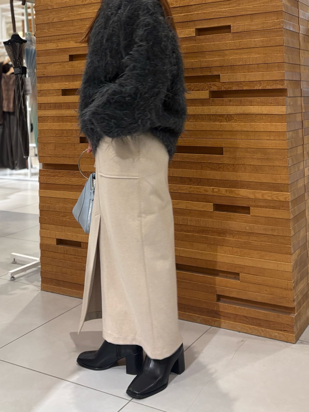 グレー系のニット/セーター、ブラウン系のスカート、ブルー系のハンドバッグを着用したレディースの秋コーディネートの3枚目の写真