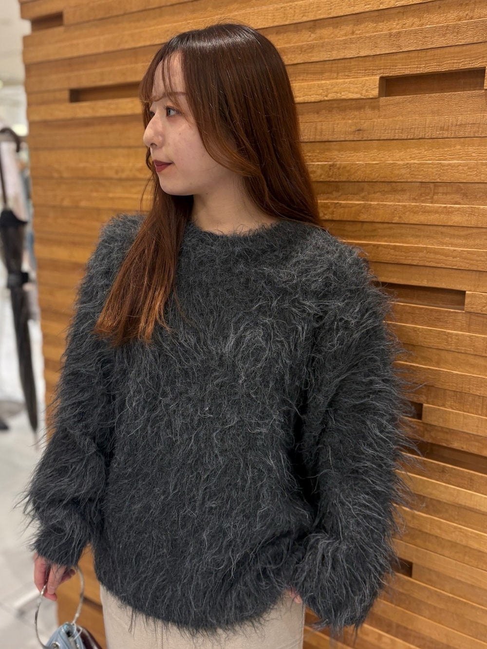 グレー系のニット/セーター、ブラウン系のスカート、ブルー系のハンドバッグを着用したレディースの秋コーディネートの2枚目の写真