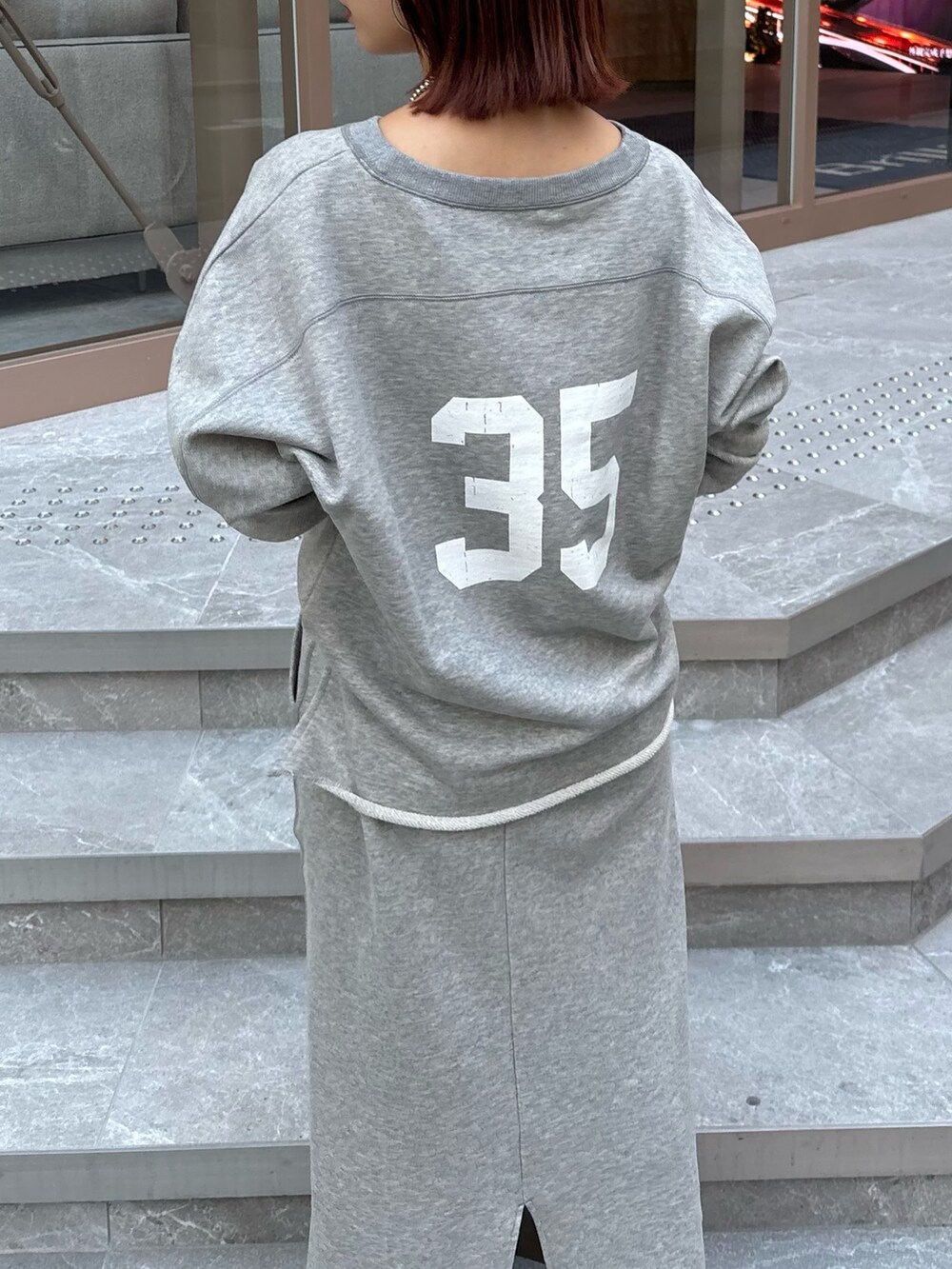 グレー系のスカート、グレー系のスウェット、ブラック系のショルダーバッグを着用したレディースの秋コーディネートの4枚目の写真