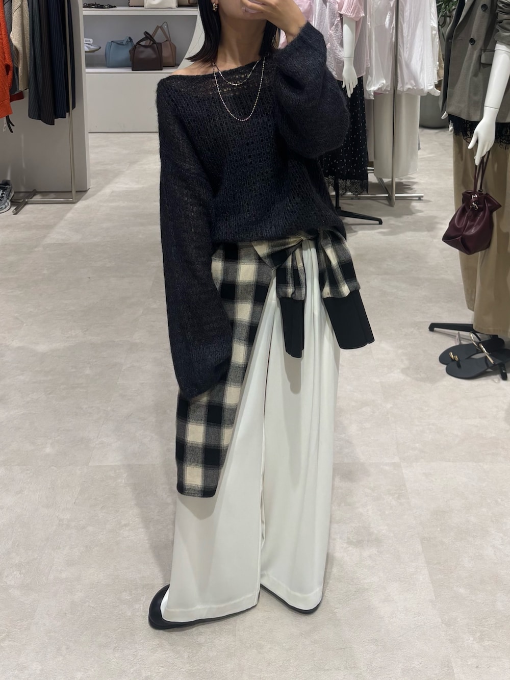 ブラック系のシャツ/ブラウス、グレー系のニット/セーター、ホワイト系のスラックスを着用したレディースの秋コーディネートの5枚目の写真