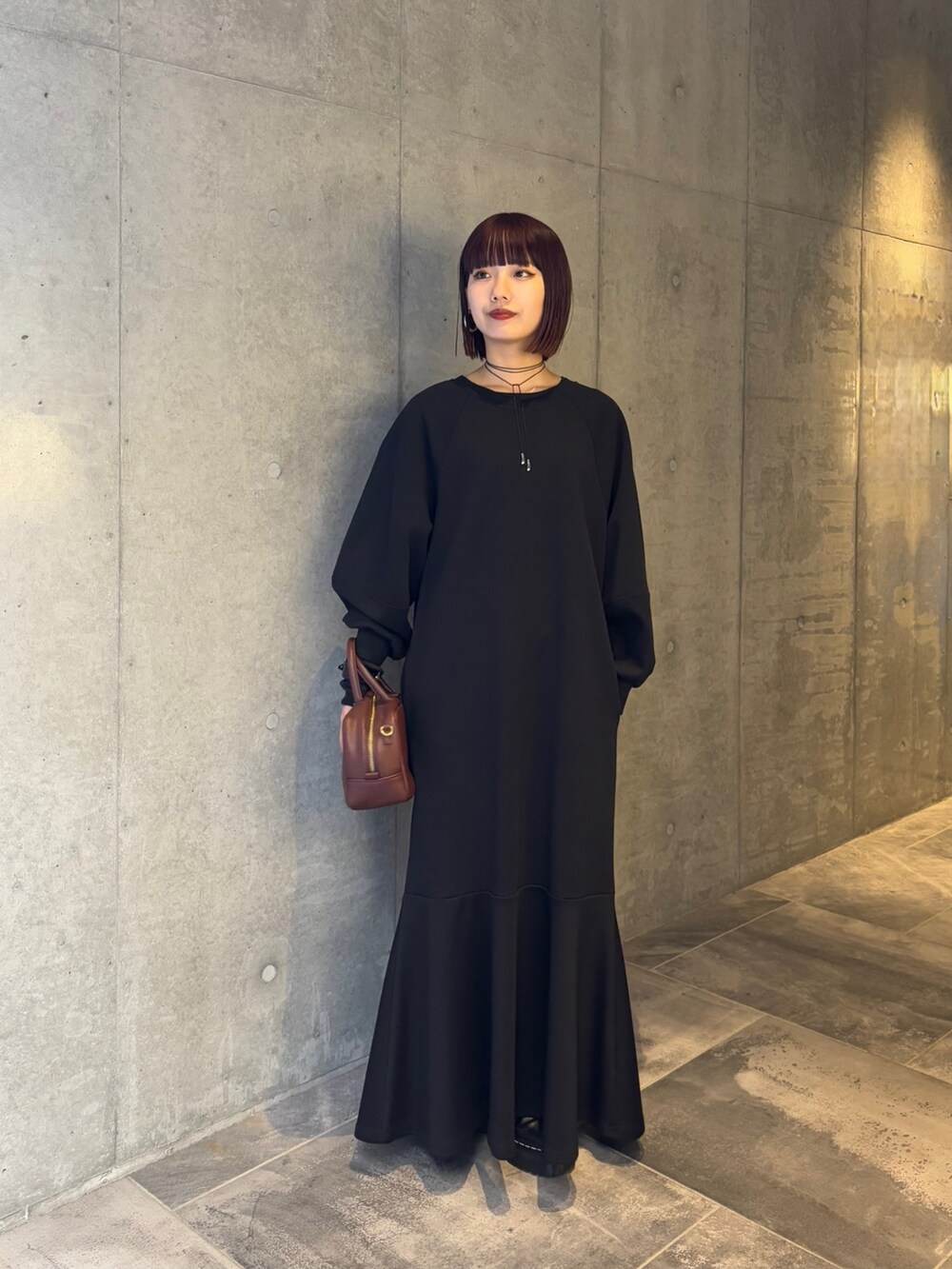 ブラック系のワンピース、ブラック系のTシャツ/カットソー、ブラウン系のショルダーバッグを着用したレディースの冬コーディネートの2枚目の写真