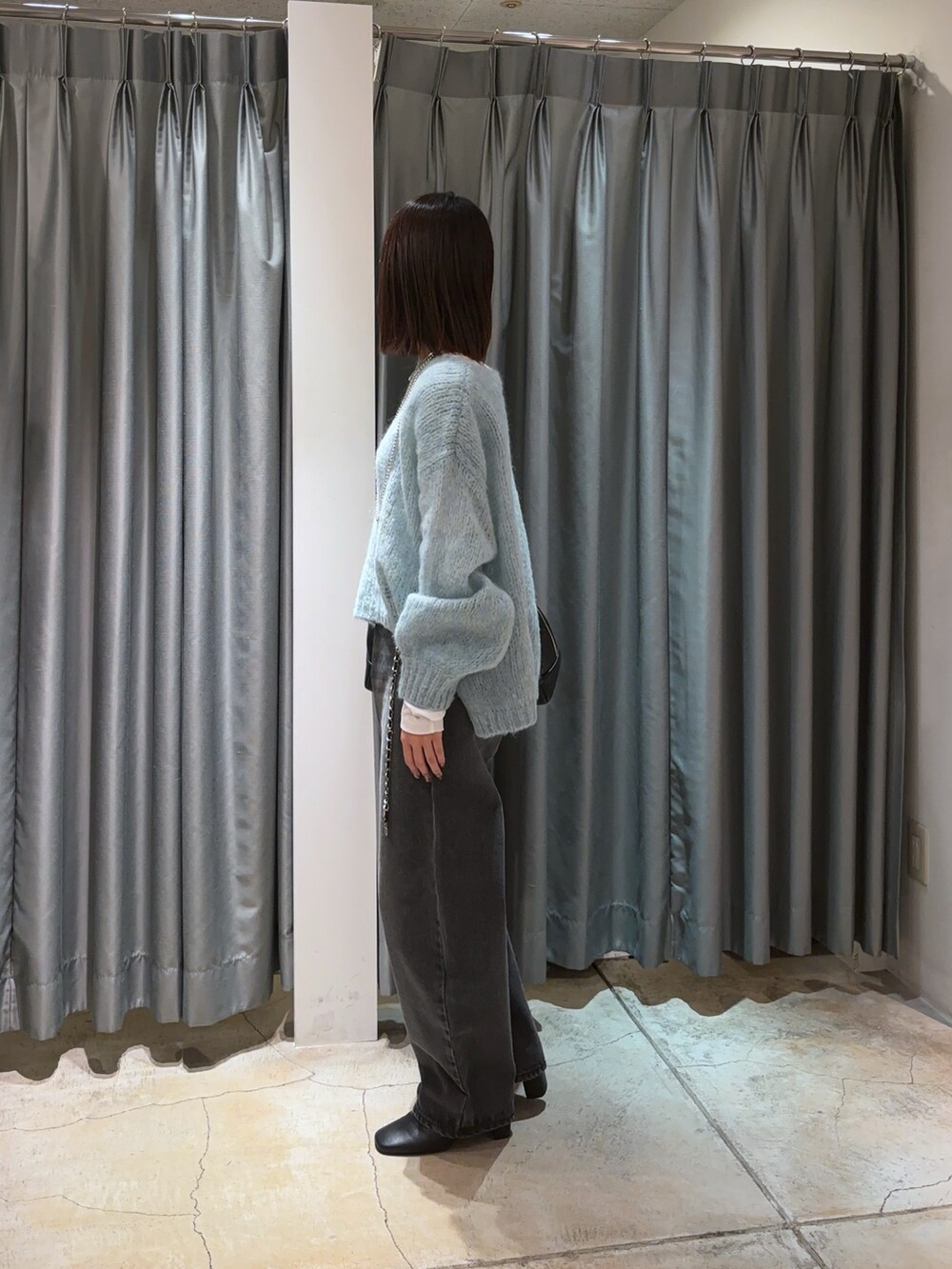 ブルー系のニット/セーター、ブラック系のデニムパンツ、ホワイト系のTシャツ/カットソーを着用したレディースの秋コーディネートの5枚目の写真