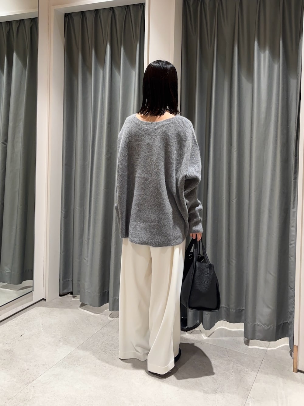 ホワイト系のスラックス、グレー系のニット/セーター、ブラック系のハンドバッグを着用したレディースの冬コーディネートの3枚目の写真