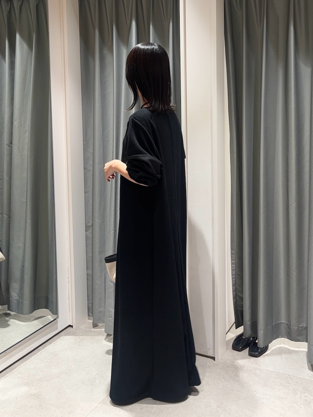 ブラック系のワンピース、ホワイト系のショルダーバッグを着用したレディースの春コーディネートの2枚目の写真