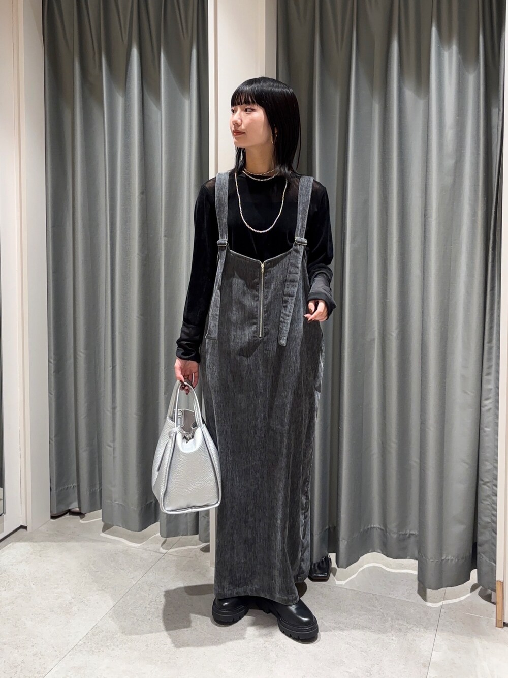 グレー系のワンピース、ブラック系のTシャツ/カットソー、シルバー系のハンドバッグを着用したレディースの冬コーディネートの2枚目の写真