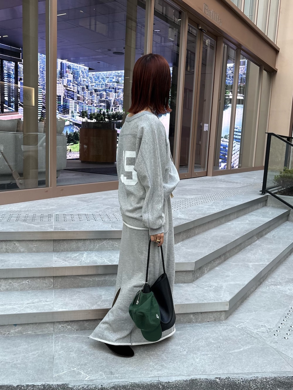 グレー系のスカート、グレー系のスウェット、ブラック系のショルダーバッグを着用したレディースの秋コーディネートの3枚目の写真