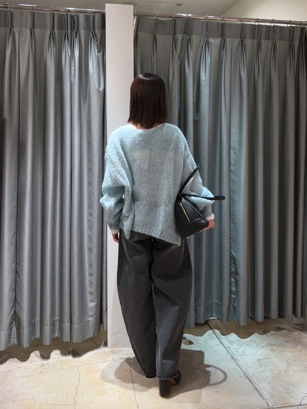 ブルー系のニット/セーター、ブラック系のデニムパンツ、ホワイト系のTシャツ/カットソーを着用したレディースの秋コーディネートの4枚目の写真