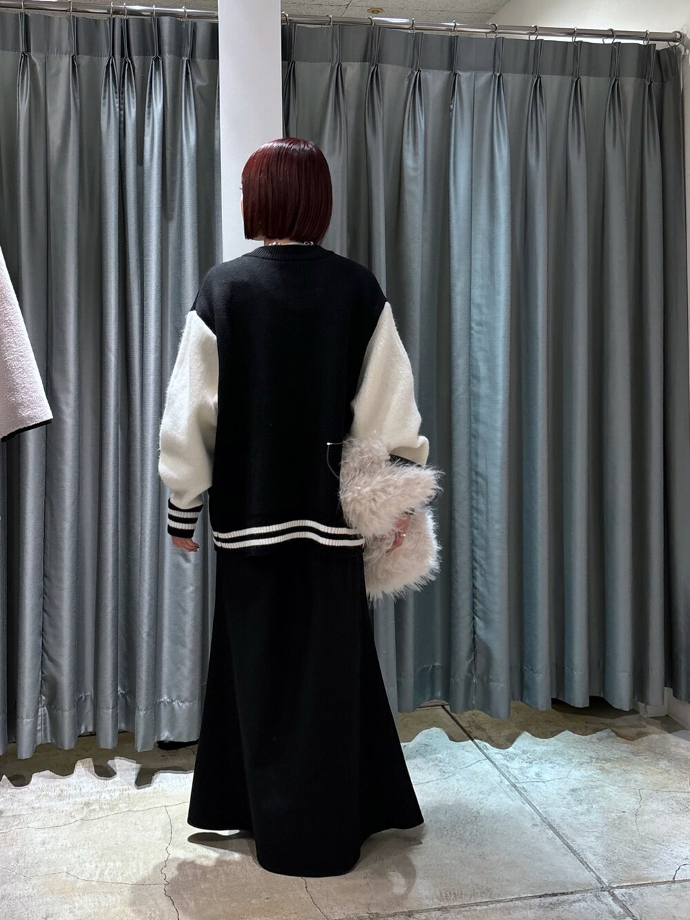 ブラック系のその他アウター、ホワイト系のショルダーバッグ、ブラック系のスカートを着用したレディースの冬コーディネートの3枚目の写真