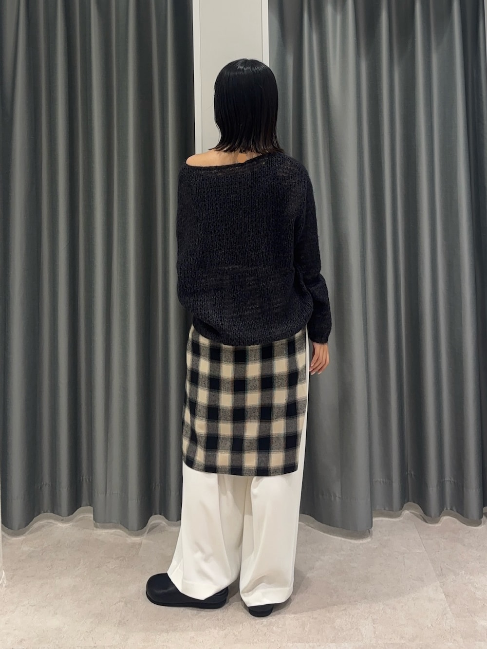 ブラック系のシャツ/ブラウス、グレー系のニット/セーター、ホワイト系のスラックスを着用したレディースの秋コーディネートの2枚目の写真