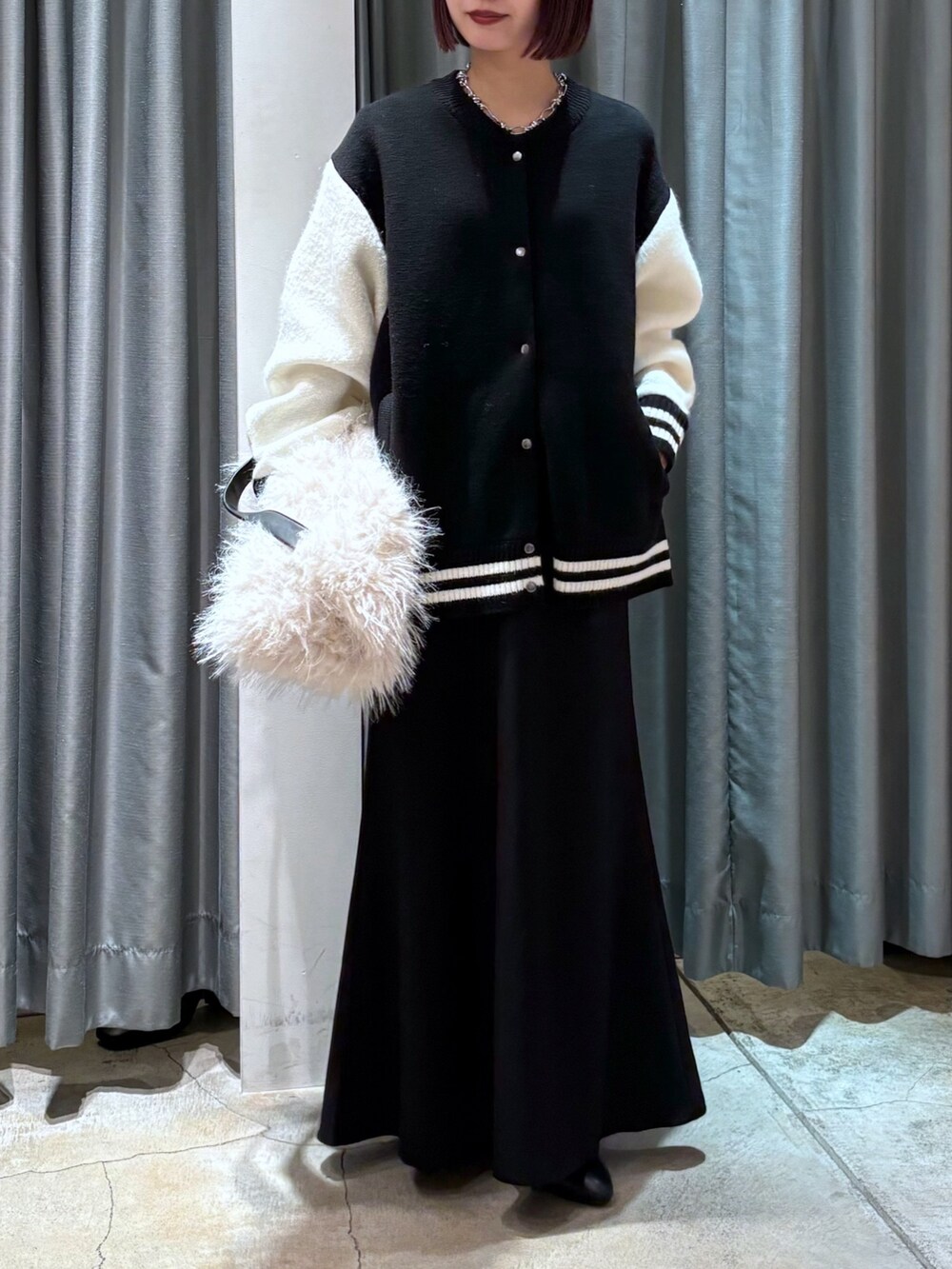 ブラック系のその他アウター、ホワイト系のショルダーバッグ、ブラック系のスカートを着用したレディースの冬コーディネートの5枚目の写真