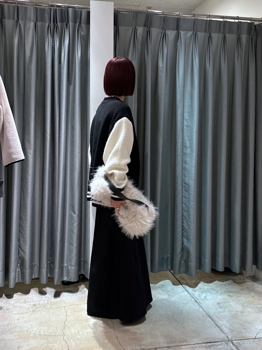 ブラック系のその他アウター、ホワイト系のショルダーバッグ、ブラック系のスカートを着用したレディースの冬コーディネートの2枚目の写真