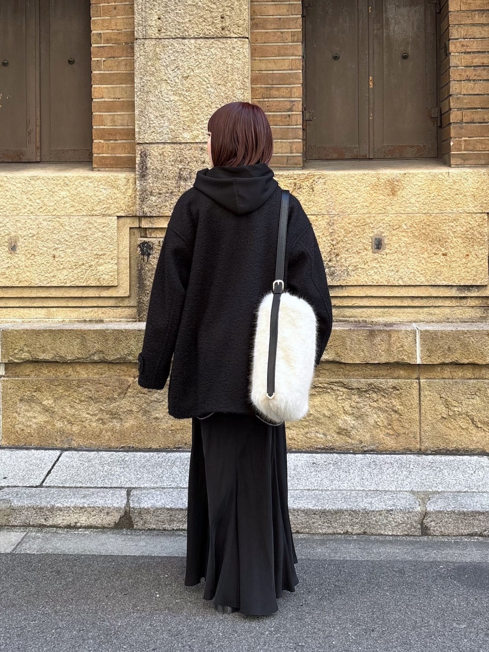 ブラック系のその他アウター、ブラック系のスカート、ホワイト系のショルダーバッグを着用したレディースの冬コーディネートの3枚目の写真