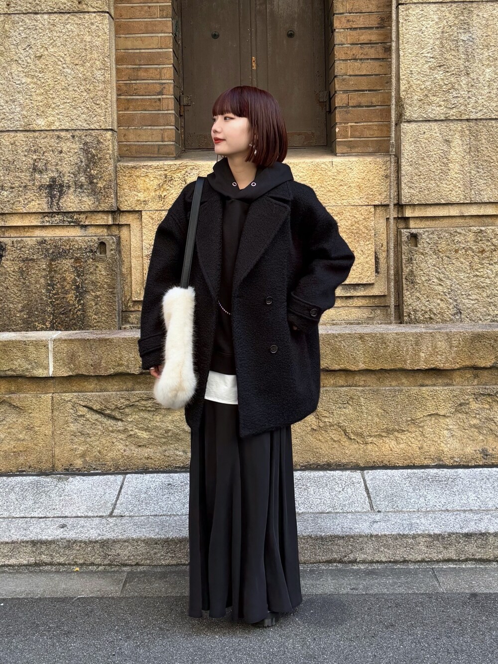 ブラック系のその他アウター、ブラック系のスカート、ホワイト系のショルダーバッグを着用したレディースの冬コーディネートの5枚目の写真