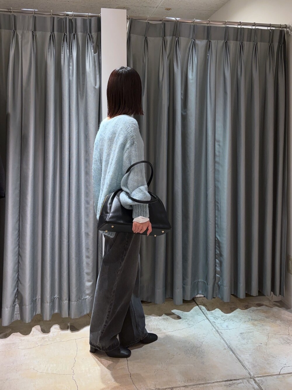 ブルー系のニット/セーター、ブラック系のデニムパンツ、ホワイト系のTシャツ/カットソーを着用したレディースの秋コーディネートの3枚目の写真