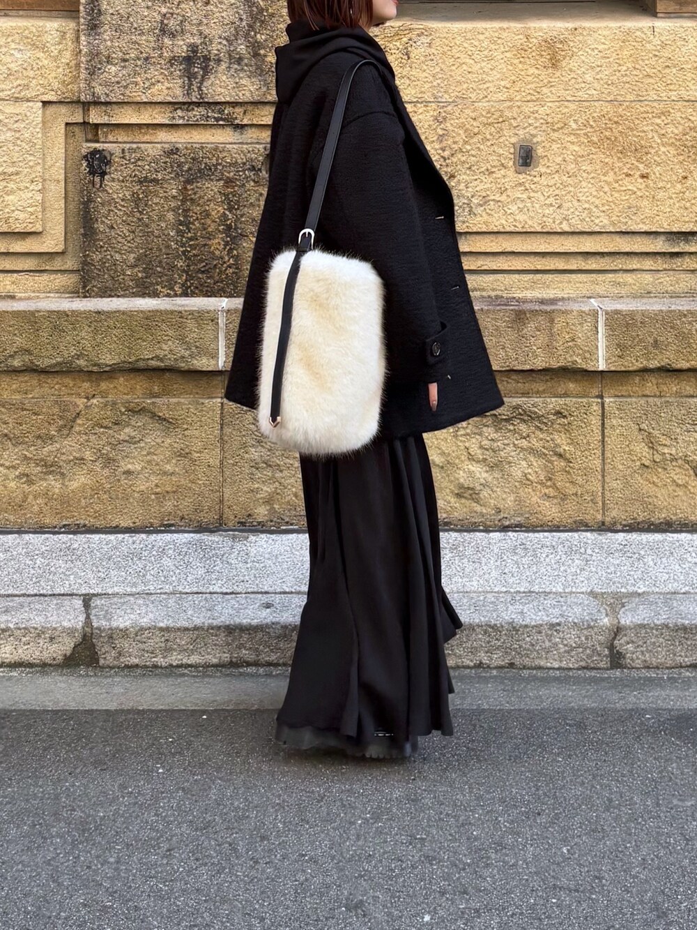 ブラック系のその他アウター、ブラック系のスカート、ホワイト系のショルダーバッグを着用したレディースの冬コーディネートの2枚目の写真