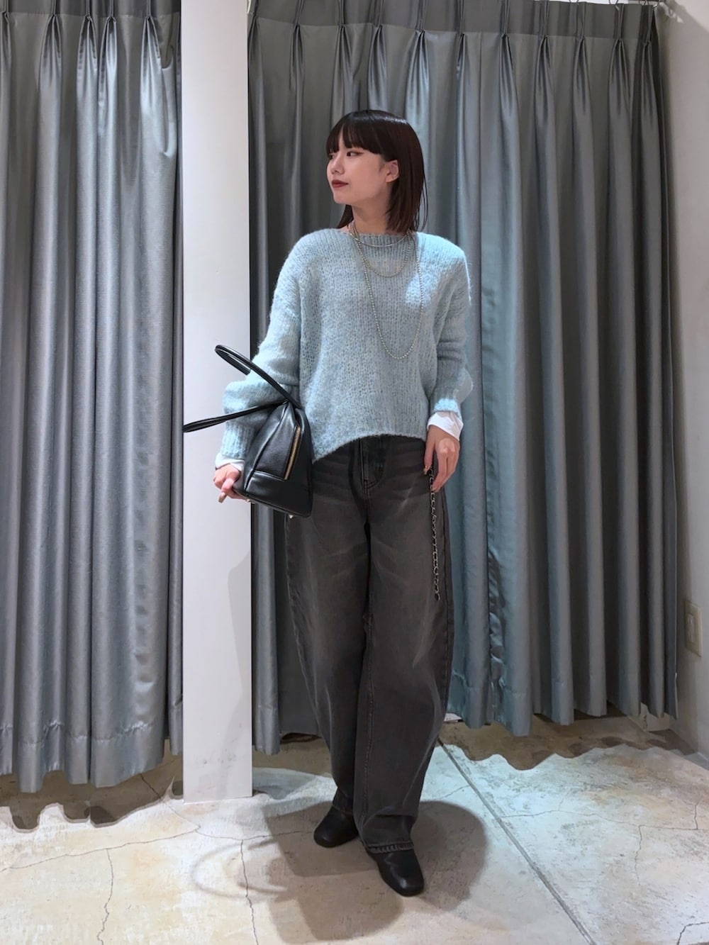 ブルー系のニット/セーター、ブラック系のデニムパンツ、ホワイト系のTシャツ/カットソーを着用したレディースの秋コーディネートの6枚目の写真