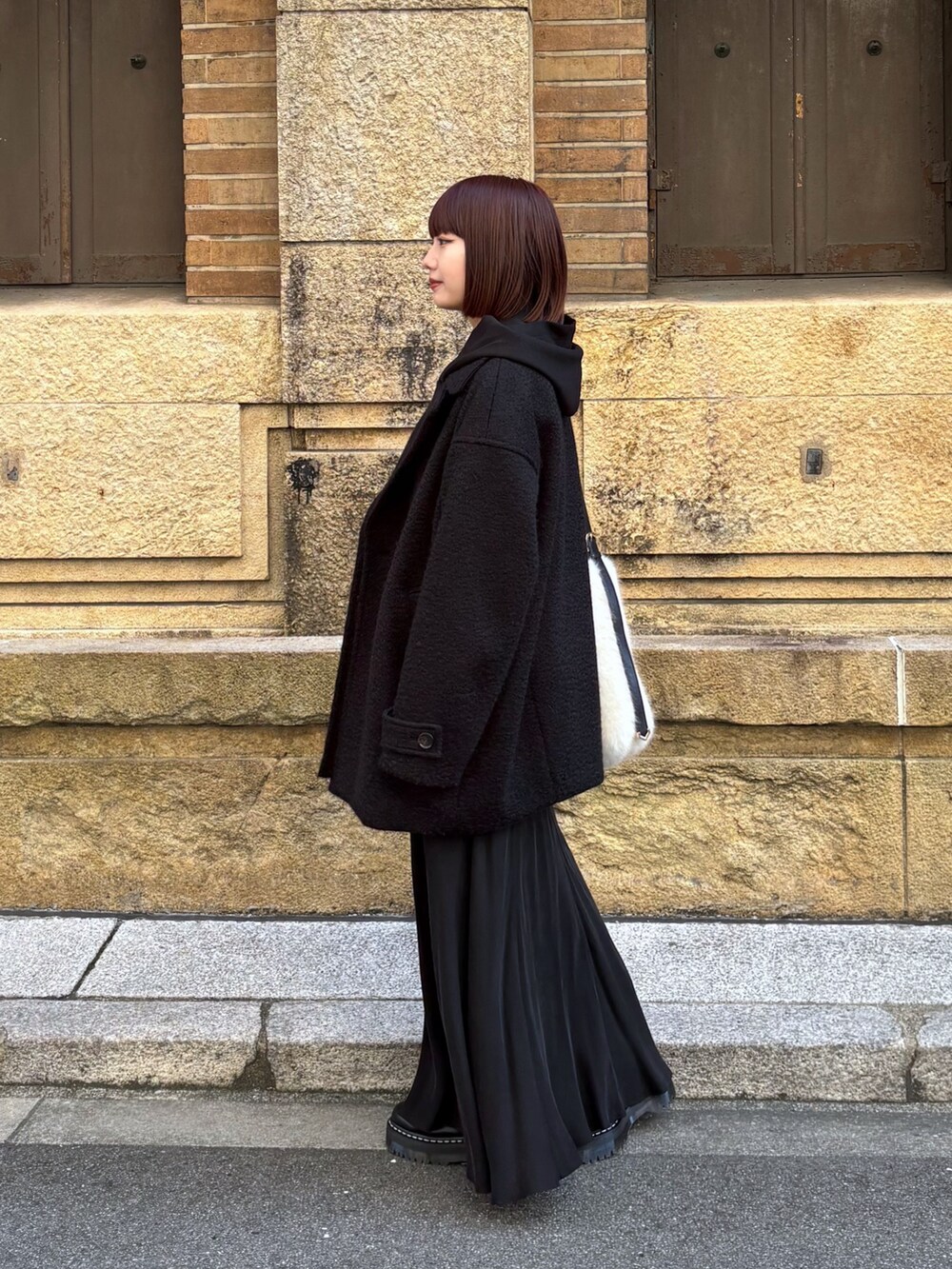 ブラック系のその他アウター、ブラック系のスカート、ホワイト系のショルダーバッグを着用したレディースの冬コーディネートの4枚目の写真