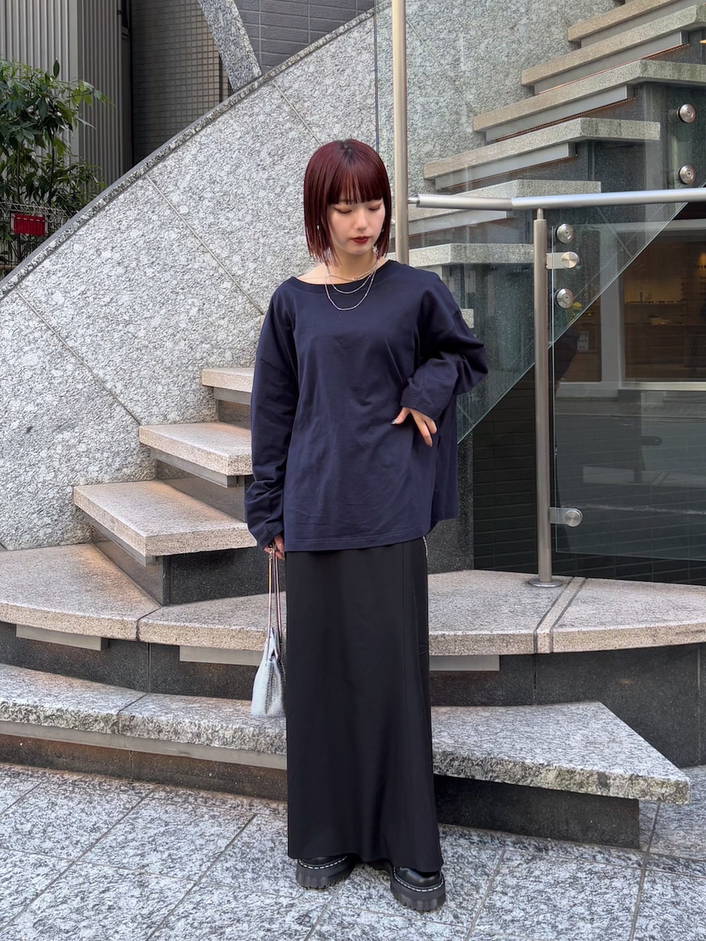ブラック系のスカート、ブルー系のTシャツ/カットソー、シルバー系のショルダーバッグを着用したレディースの冬コーディネートの2枚目の写真