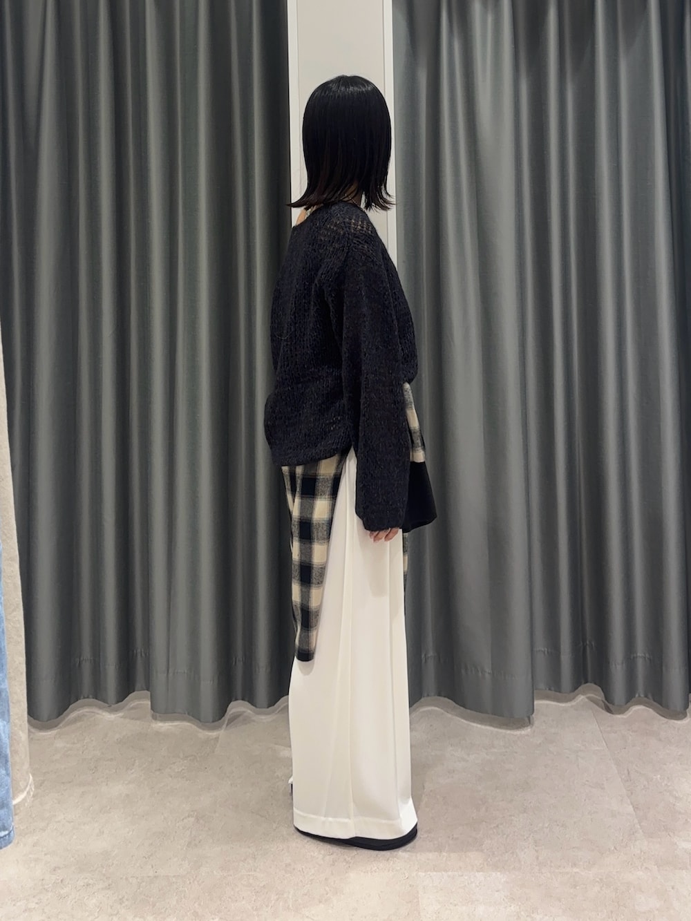 ブラック系のシャツ/ブラウス、グレー系のニット/セーター、ホワイト系のスラックスを着用したレディースの秋コーディネートの3枚目の写真
