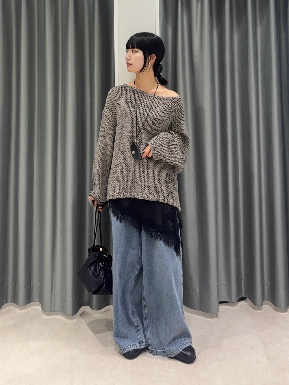 グレー系のニット/セーター、ブラック系のシャツ/ブラウス、ブルー系のデニムパンツを着用したレディースの秋コーディネートの2枚目の写真