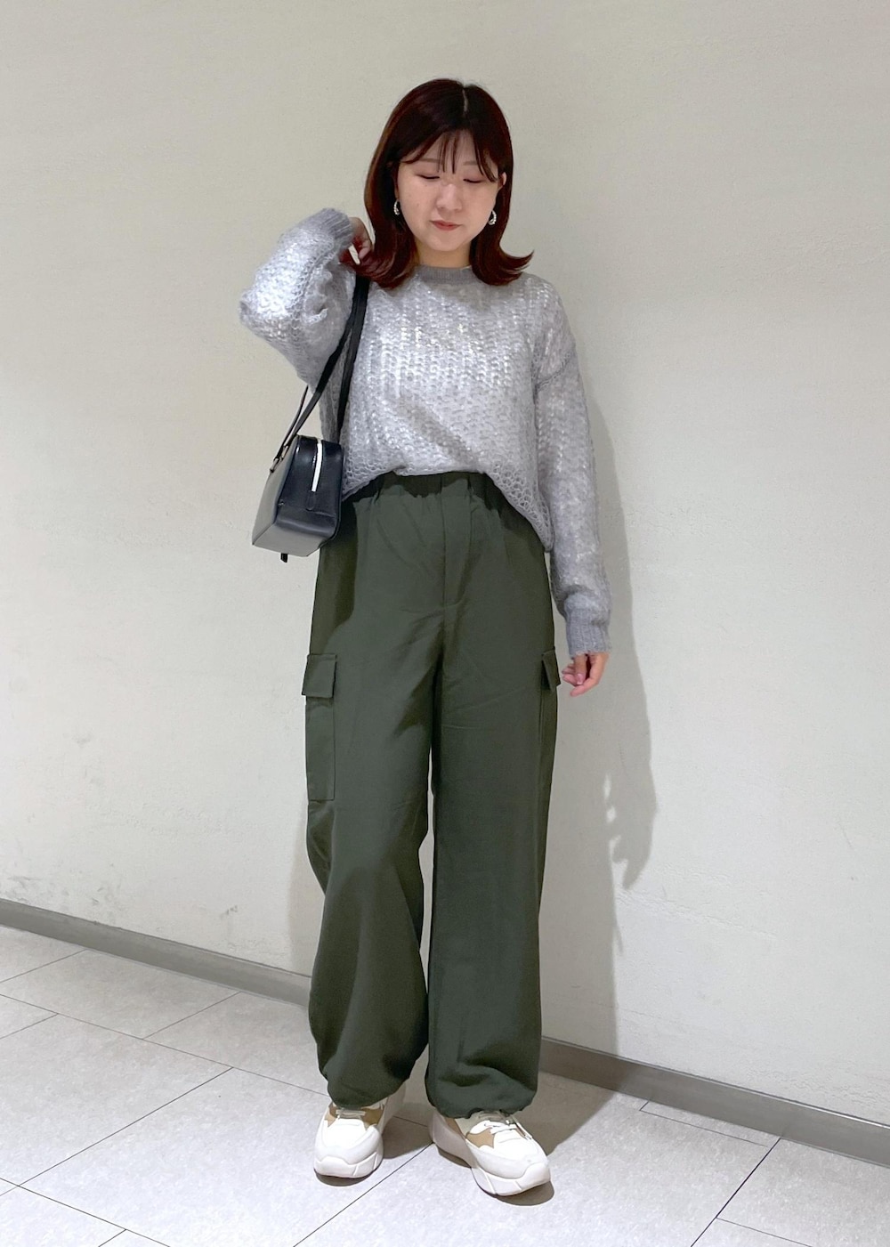 グレー系のニット/セーター、グリーン系のカーゴパンツ、ブラック系のボストンバッグを着用したレディースの秋コーディネートの2枚目の写真