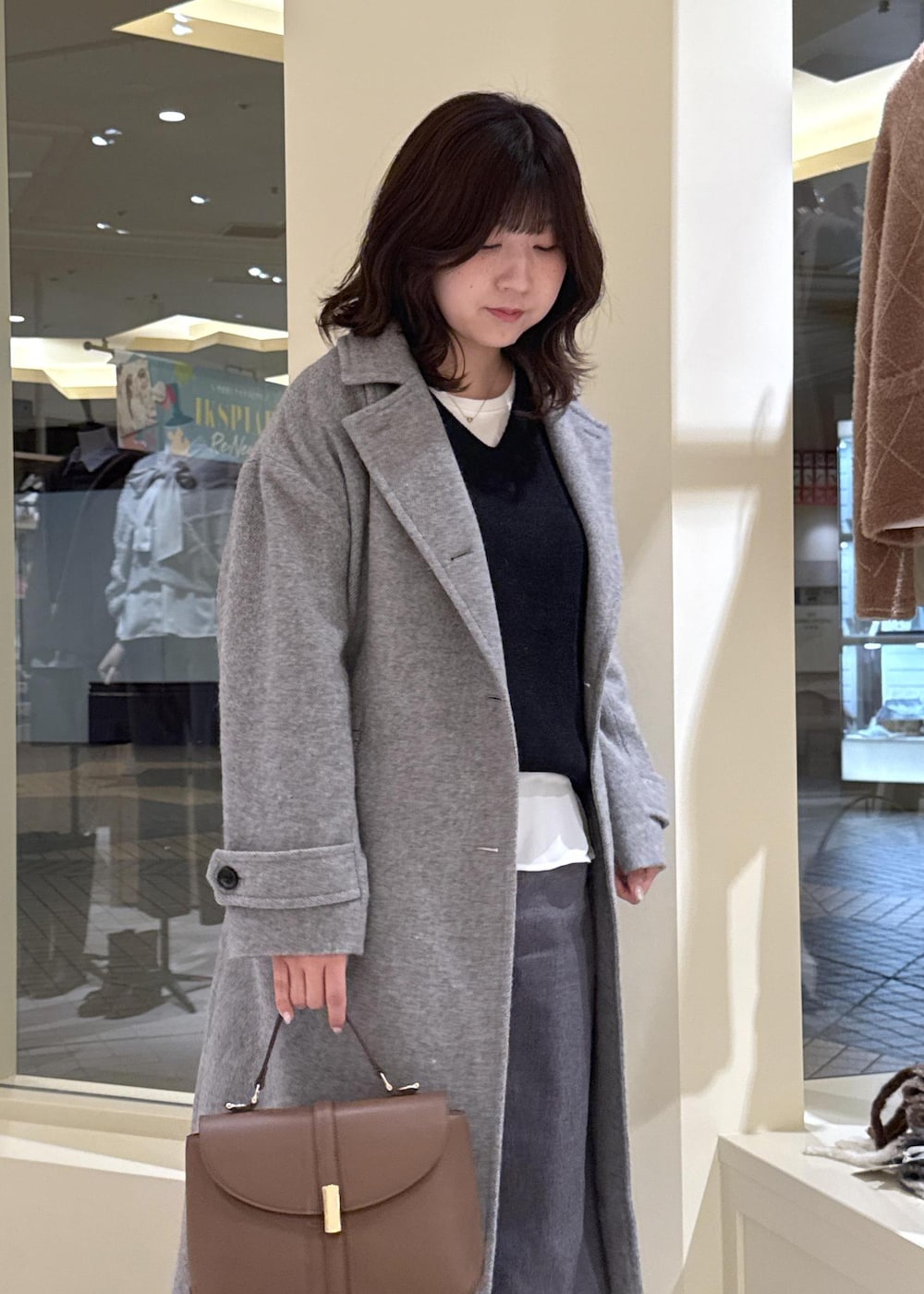 ホワイト系のTシャツ/カットソー、ブラック系のニット/セーター、グレー系のチェスターコートを着用したレディースの冬コーディネートの6枚目の写真