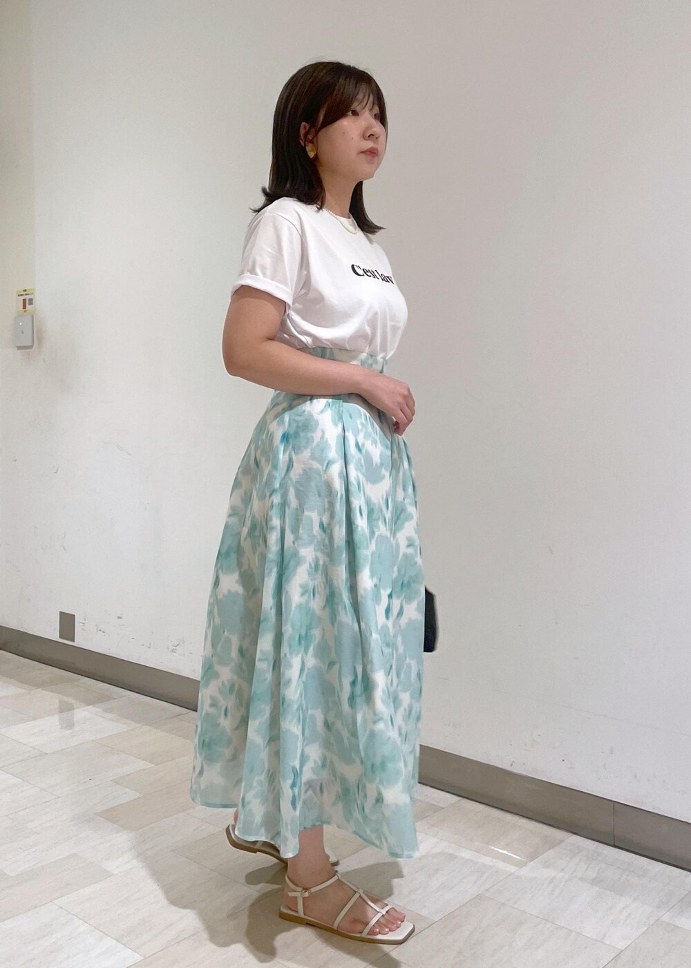 ブルー系のスカート、ブラック系のショルダーバッグ、ホワイト系のTシャツ/カットソーを着用したレディースの夏コーディネートの4枚目の写真