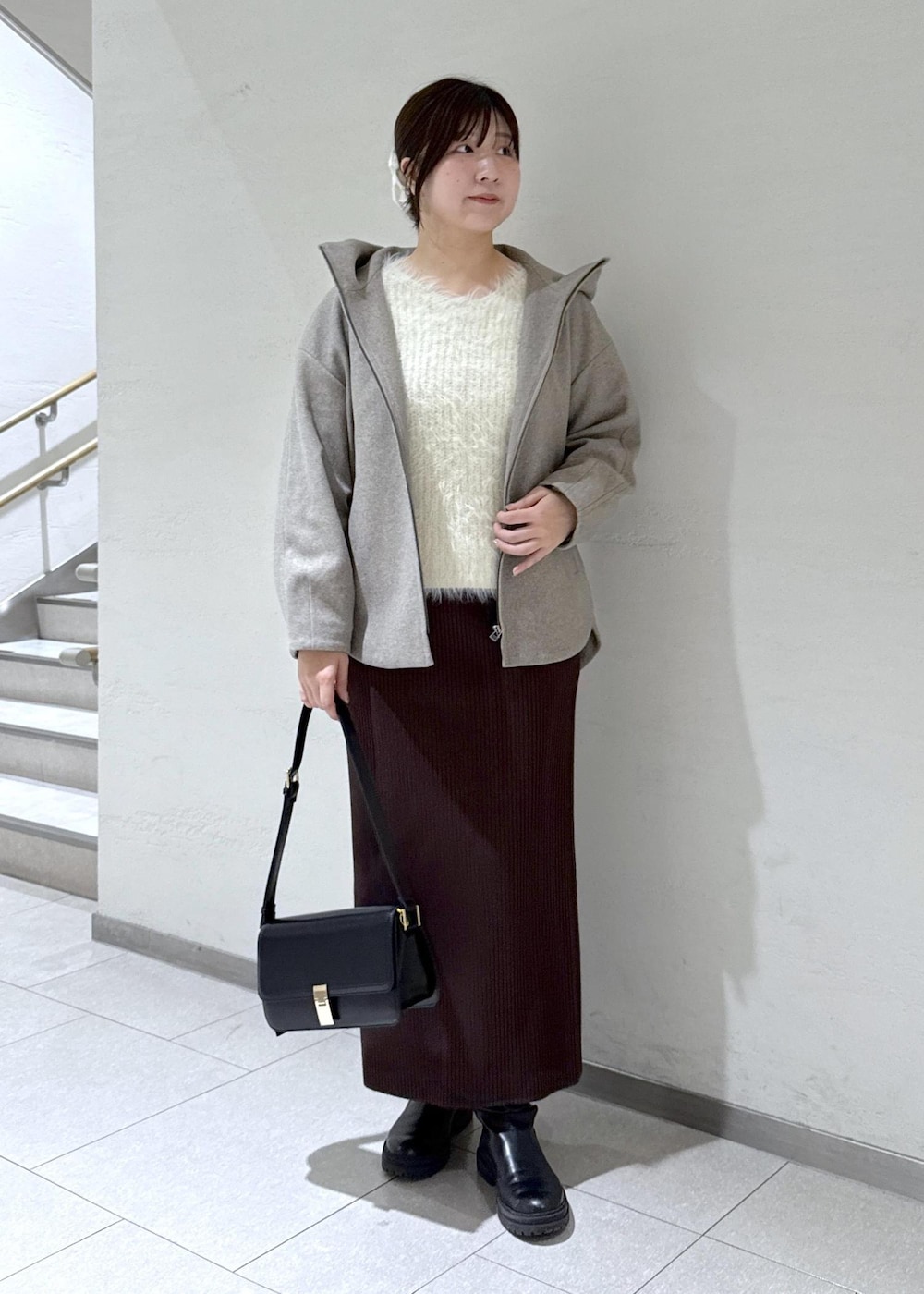ブラック系のショルダーバッグ、ブラウン系のその他アウター、ホワイト系のニット/セーターを着用したレディースの冬コーディネートの2枚目の写真