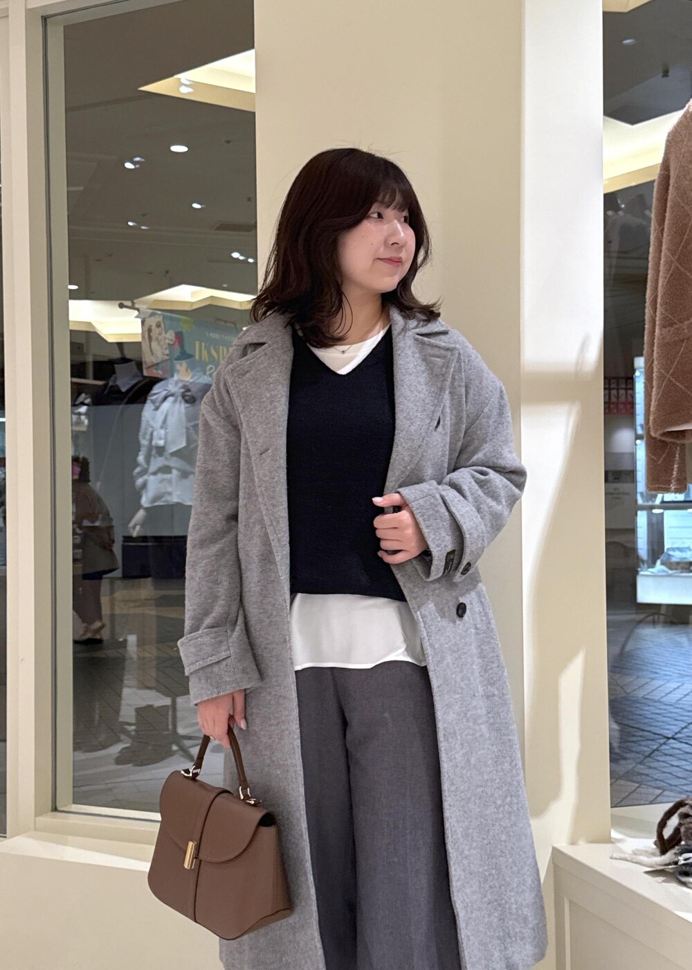 ホワイト系のTシャツ/カットソー、ブラック系のニット/セーター、グレー系のチェスターコートを着用したレディースの冬コーディネートの5枚目の写真