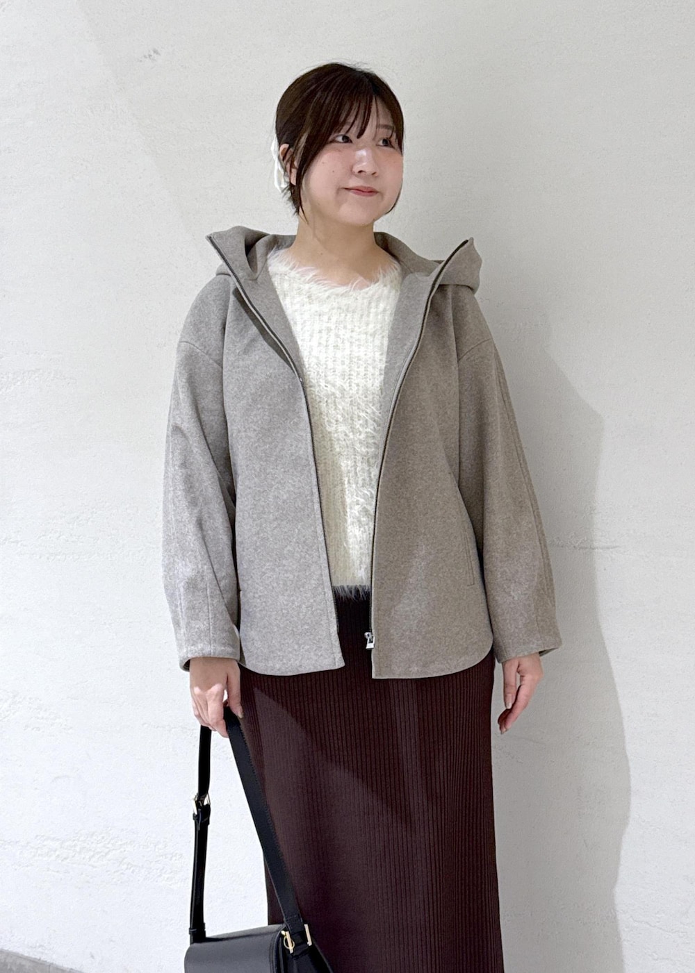 ブラック系のショルダーバッグ、ブラウン系のその他アウター、ホワイト系のニット/セーターを着用したレディースの冬コーディネートの4枚目の写真