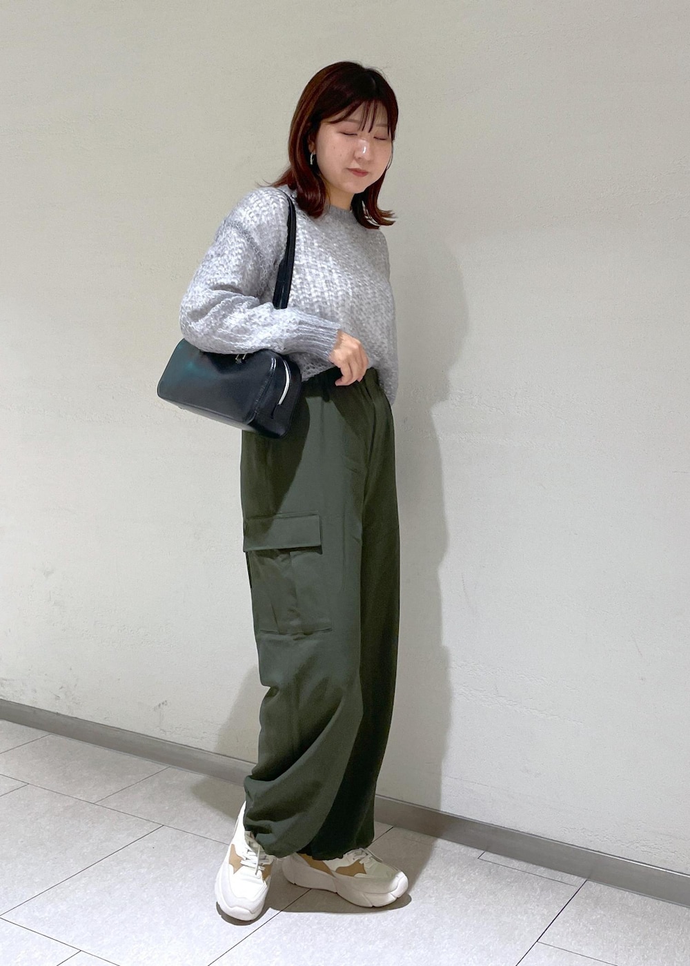 グレー系のニット/セーター、グリーン系のカーゴパンツ、ブラック系のボストンバッグを着用したレディースの秋コーディネートの3枚目の写真
